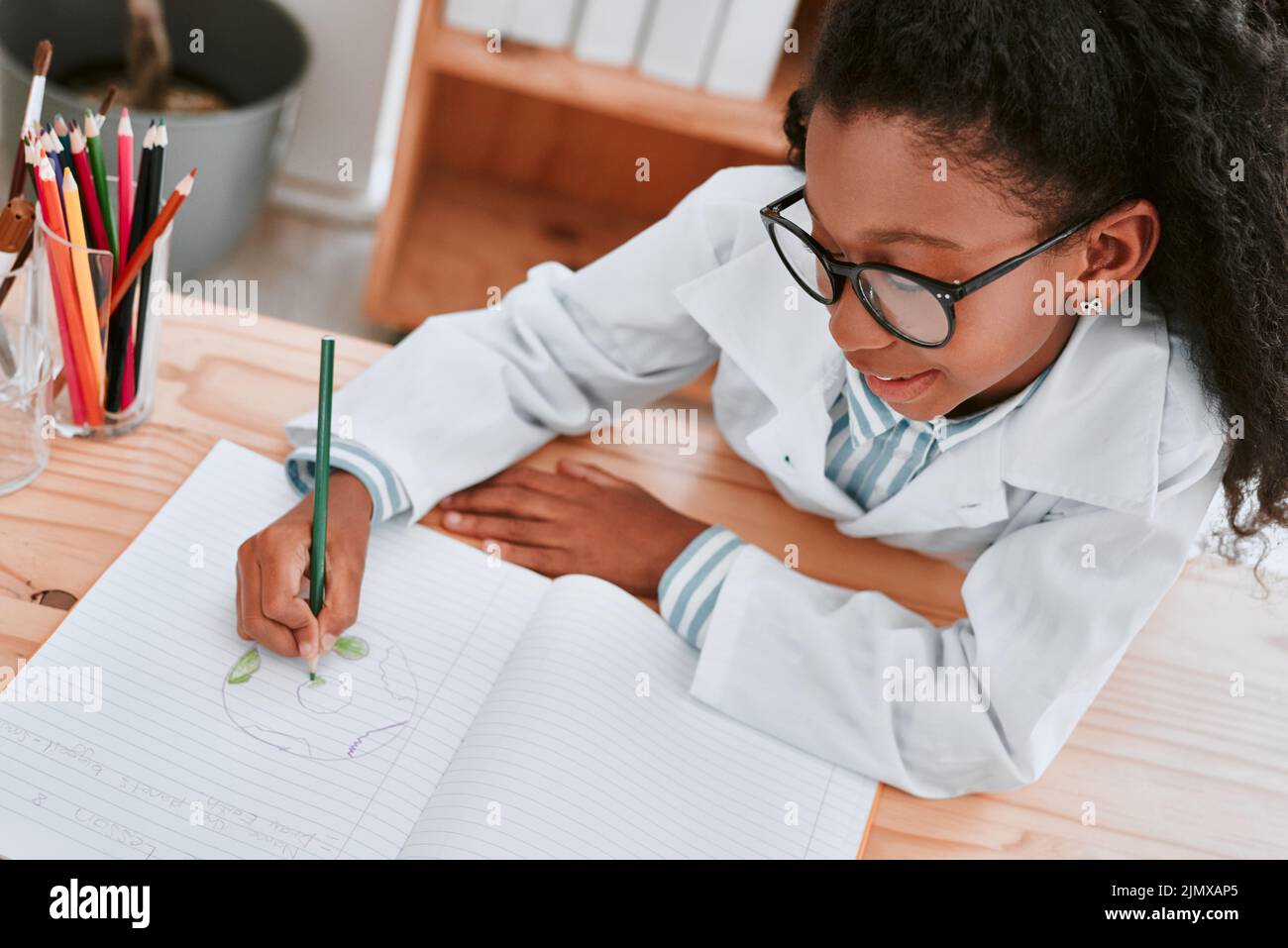 Sometimes you have to draw things into perspective. an adorable young school girl drawing a diagram in her exercise book in science class at school. Stock Photo