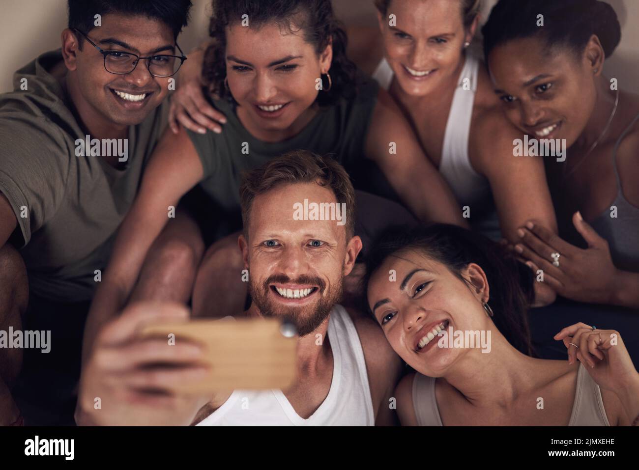 Gym selfies are always the best. a group of young people taking selfies after working out together in a yoga class. Stock Photo