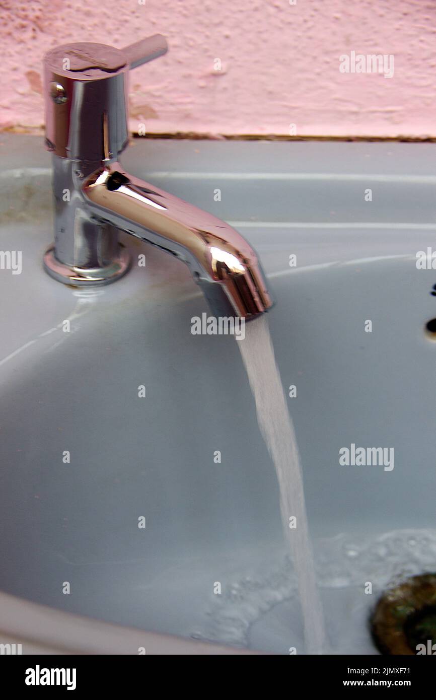 Water gushing through tap of gray color wash basin Stock Photo