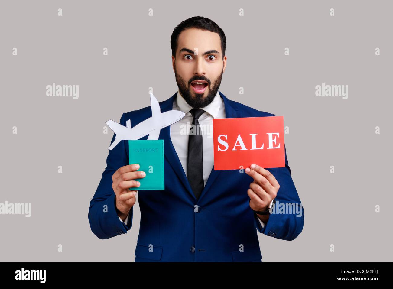 Surprised bearded man holding passport with paper air plane and sale