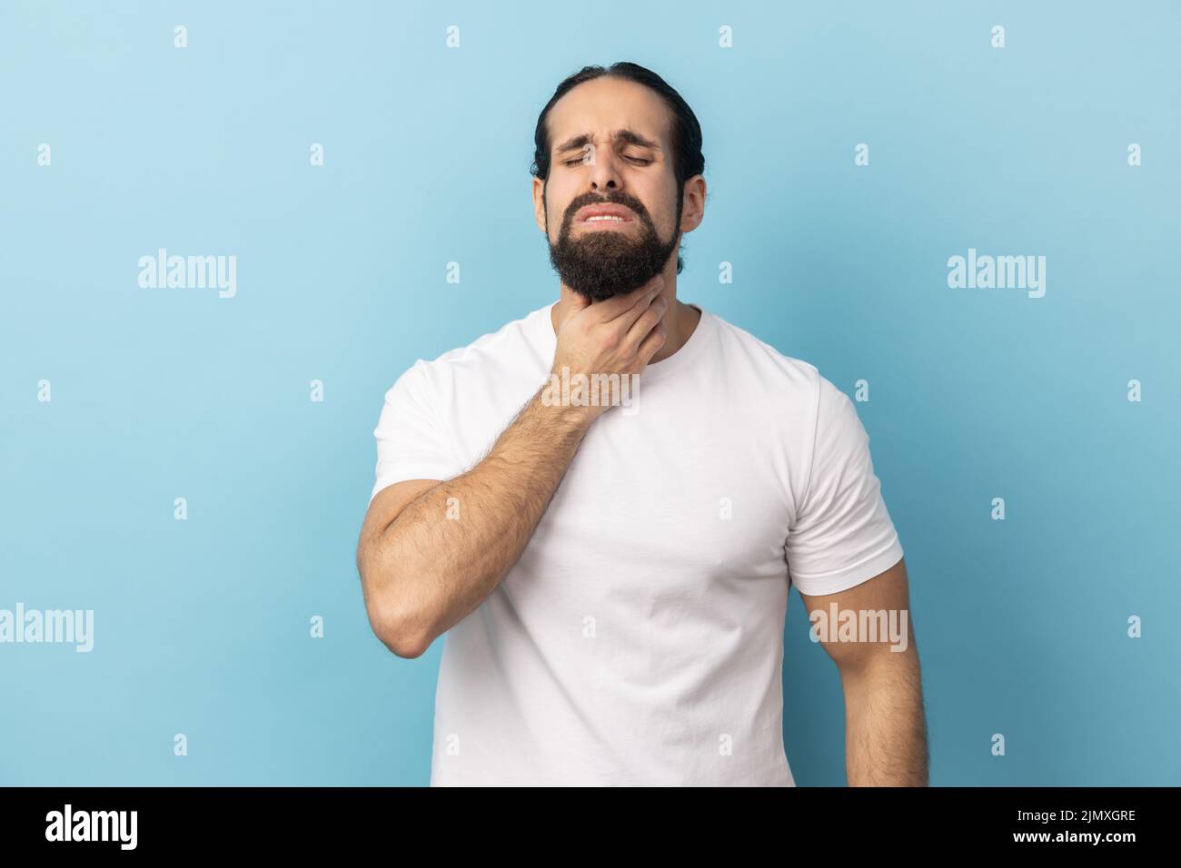 Portrait of unhealthy man with beard wearing white T-shirt suffering ...