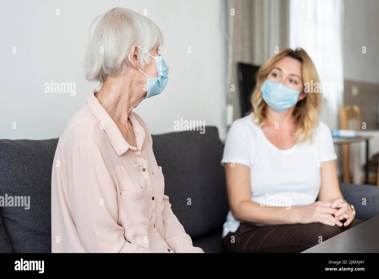 Woman visiting her relative nursing home wearing medical mask Stock Photo