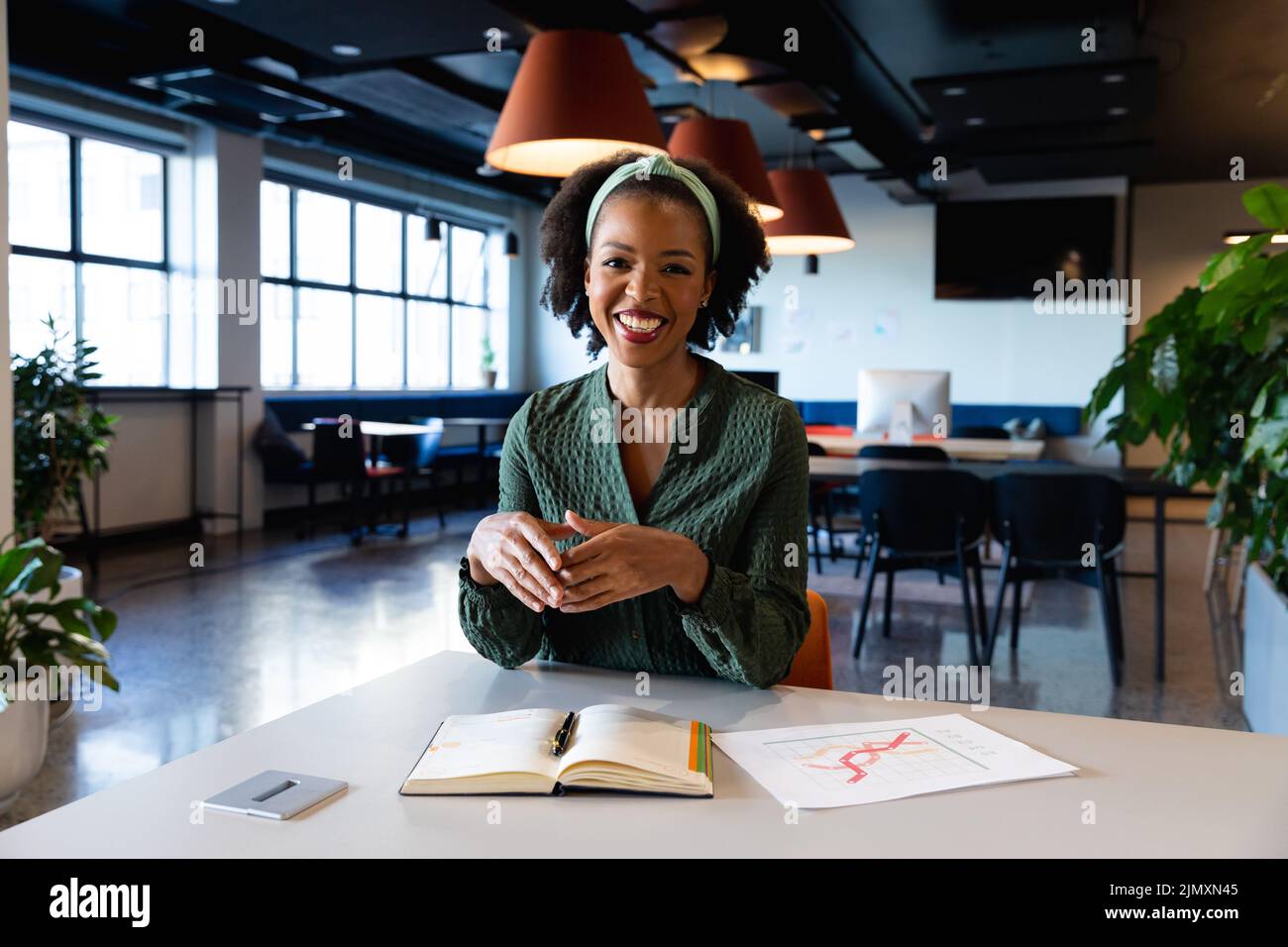 Portrait of smiling african american young businesswoman with diary at ...