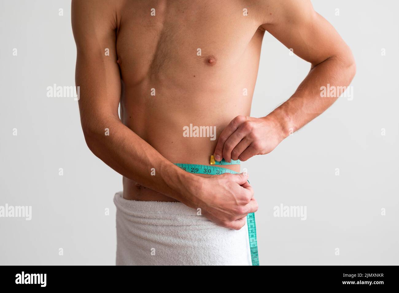 Front view shirtless man measuring his waste with tape Stock Photo