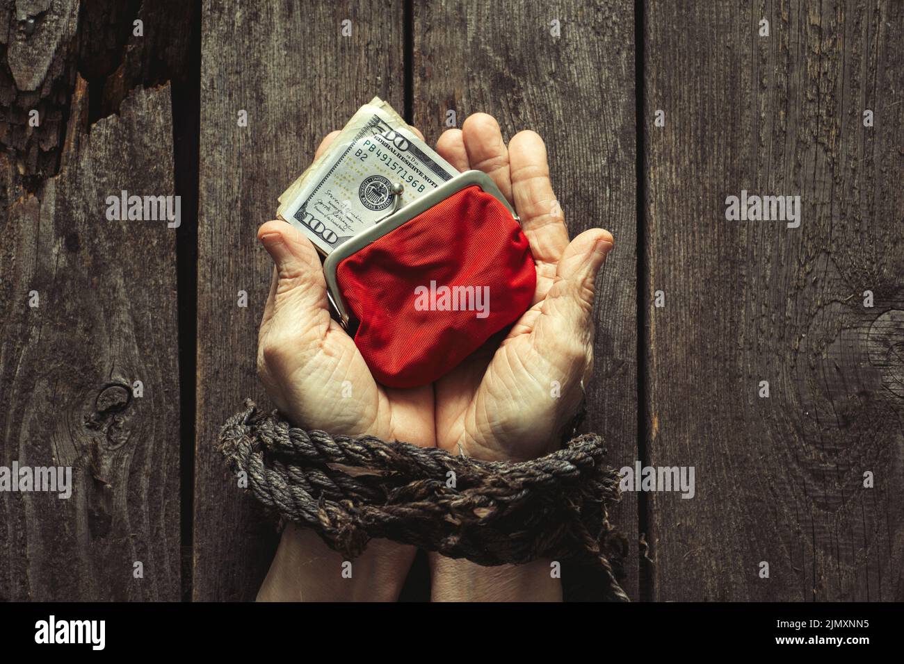red wallet with American dollars in the girl's tied hands on the table Stock Photo