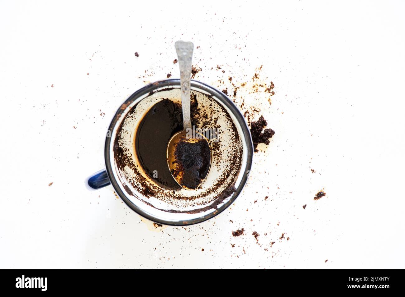 a cup with overturned coffee on a white background and a teaspoon lies next to it, spilled coffee on a white background Stock Photo