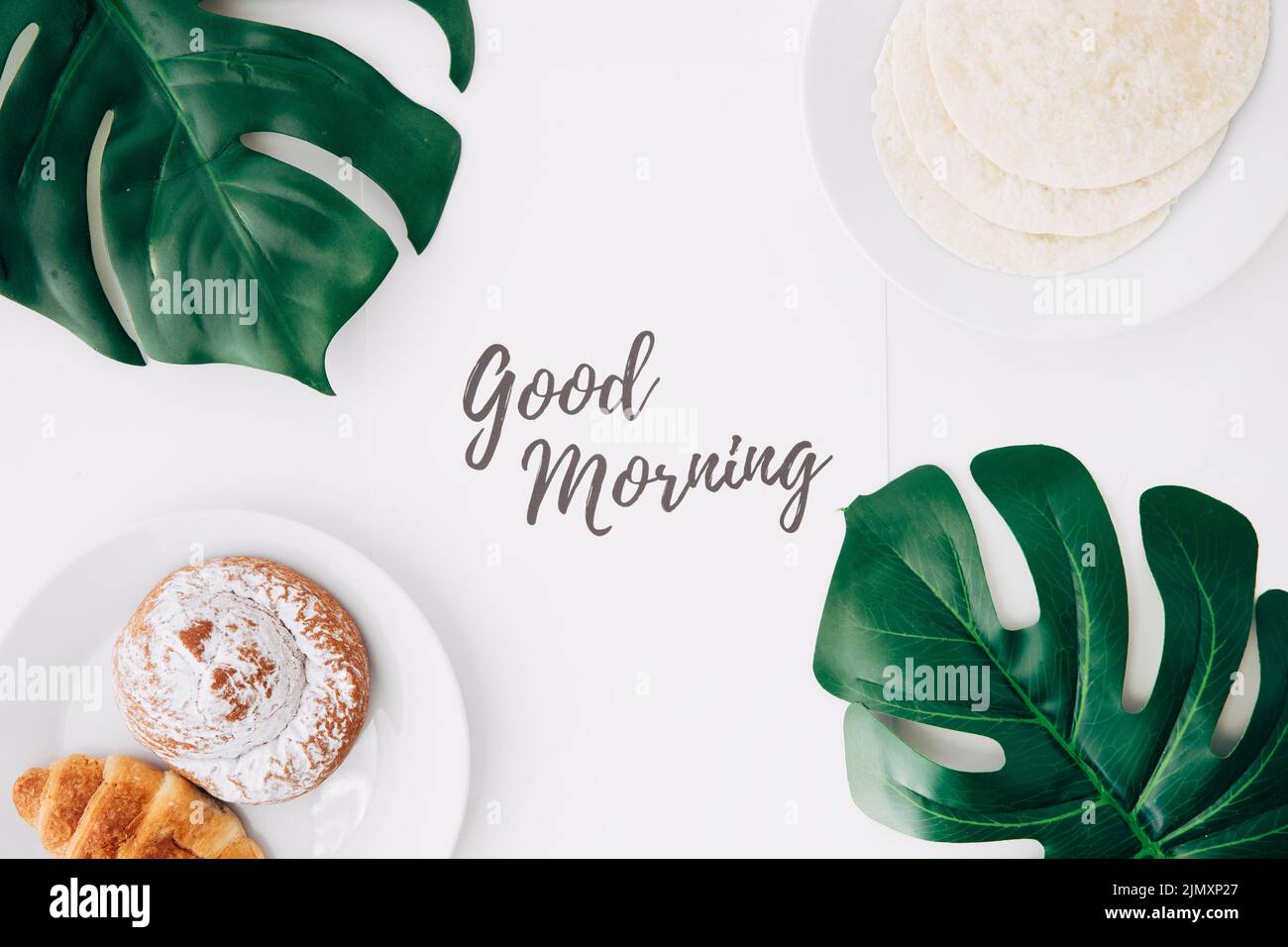 Fresh flour tortillas baked bun croissant breakfast with good morning text paper green monster leaves white background Stock Photo