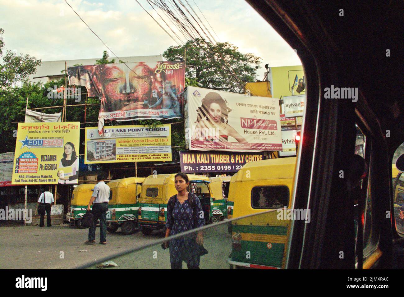 Street walkers and rickshaws in a background of commercial billboard in Kolkata, West Bengal, India. Stock Photo