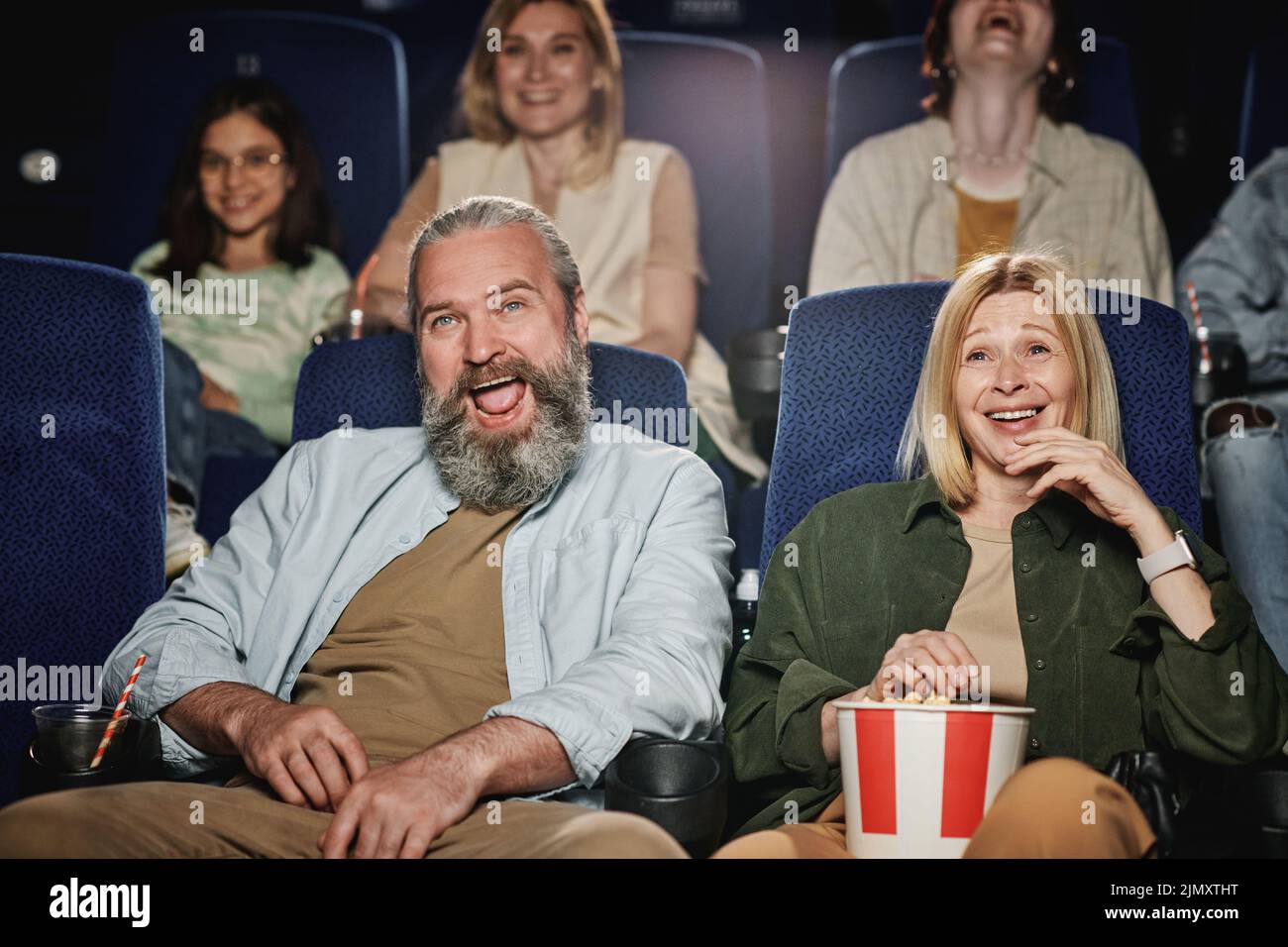 Group of people spending weekend at cinema watching funny comedy movie, selective focus shot Stock Photo