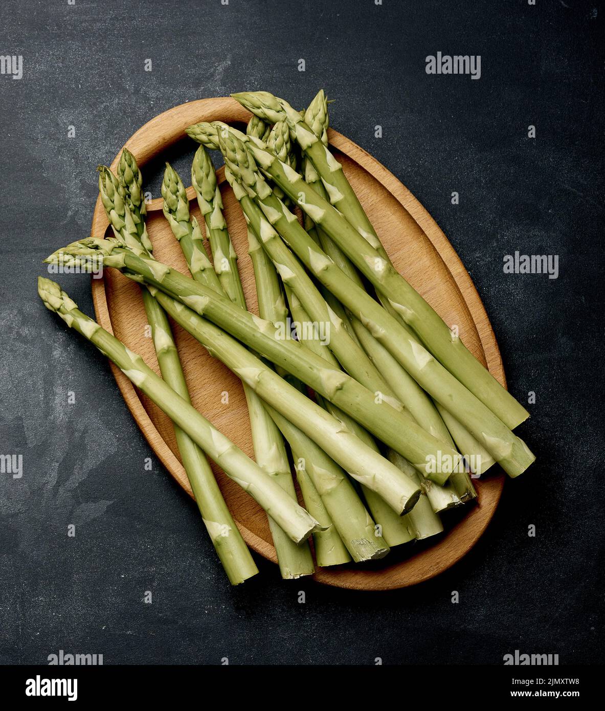 Bunch of fresh raw asparagus on a wooden black kitchen board, a healthy product Stock Photo
