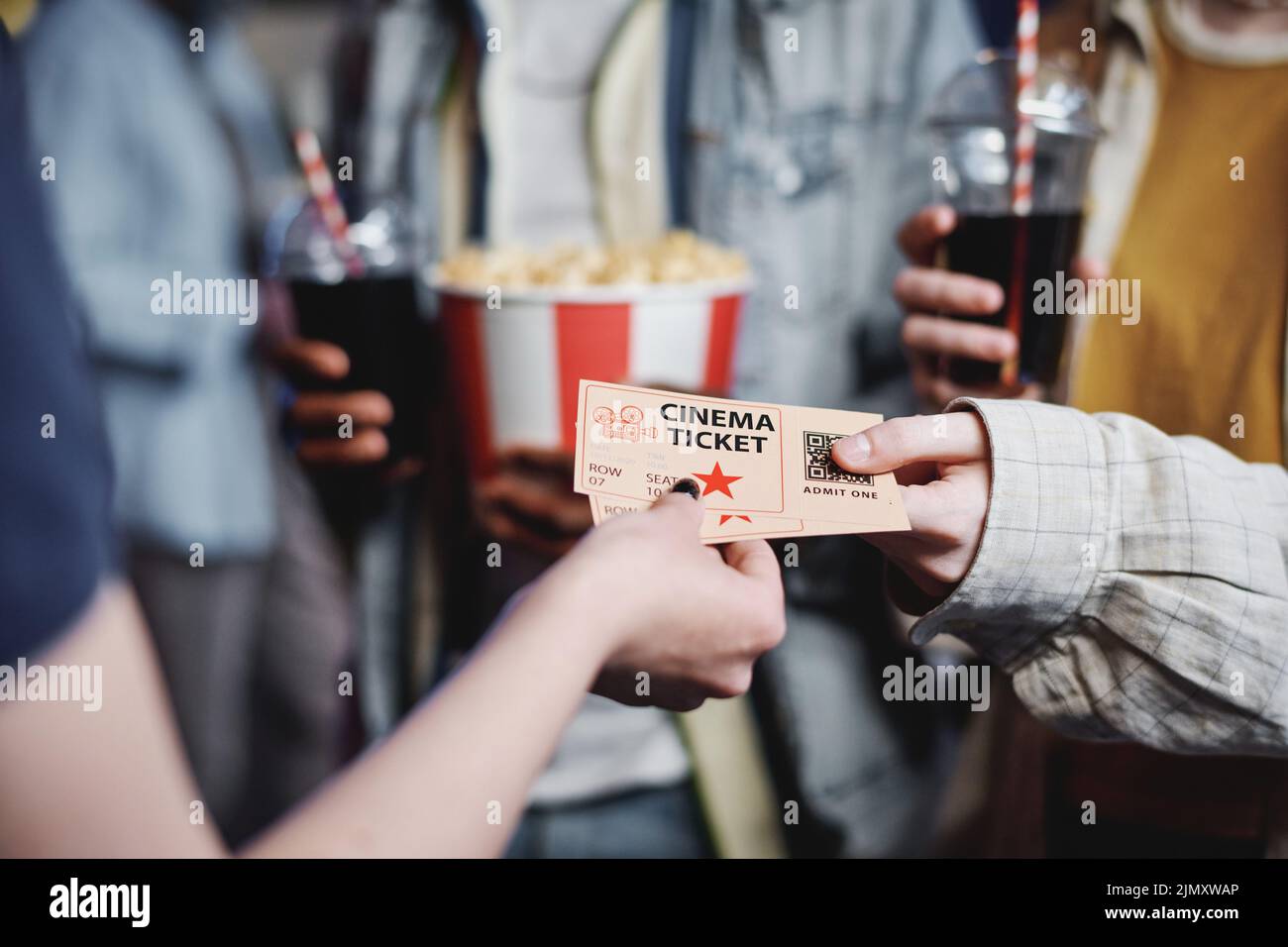 Unrecognizable people giving tickets for movie to cinema worker to enter hall, selective focus shot Stock Photo
