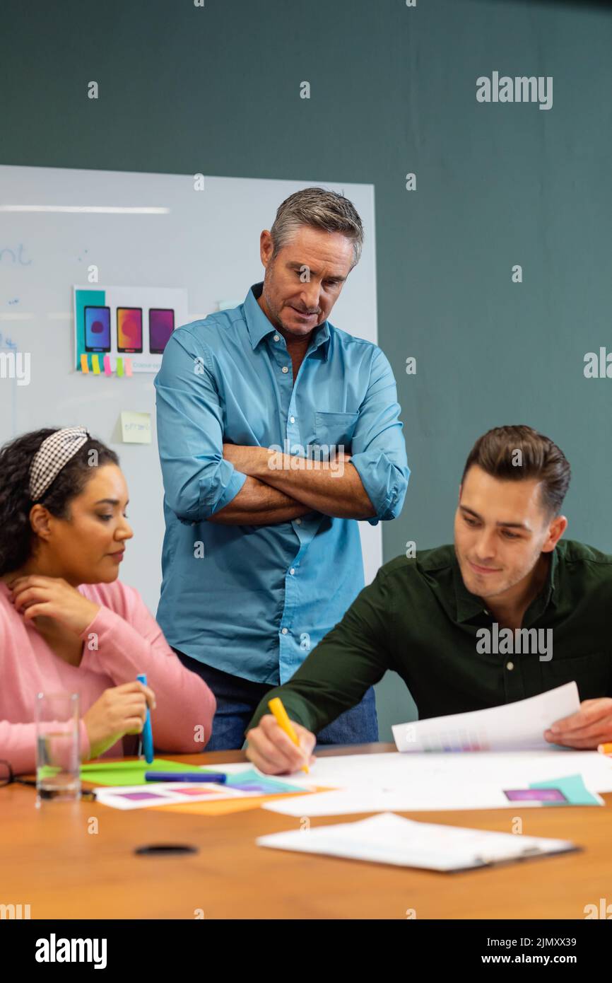 Manager looking at multiracial colleagues discussing business strategy in meeting at creative office Stock Photo