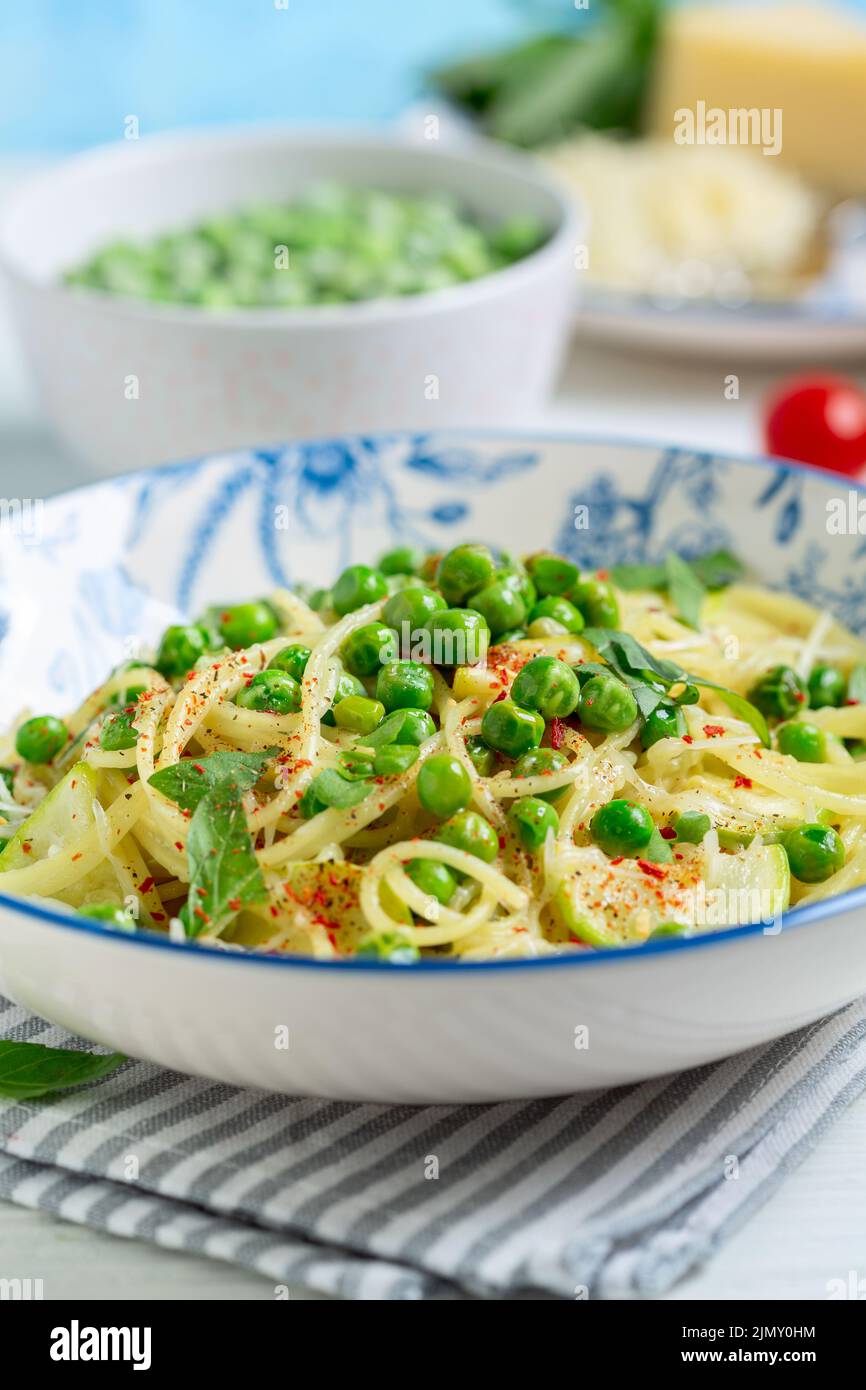 Spaghetti with zucchini and green peas. Stock Photo