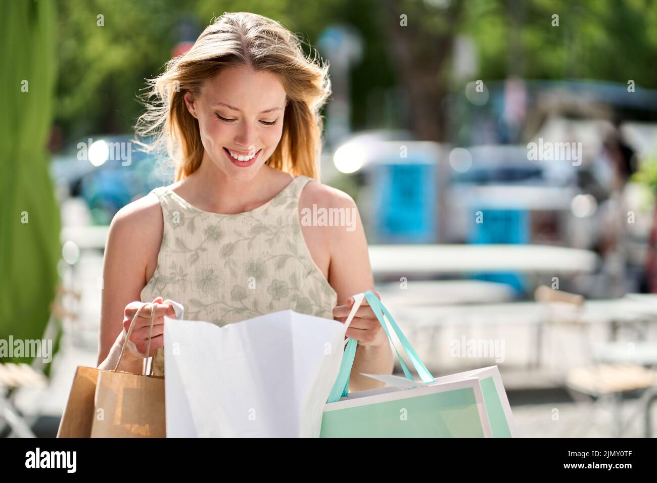 Smiling fashion woman shopper holding shopping bags walking on summer street. Stock Photo