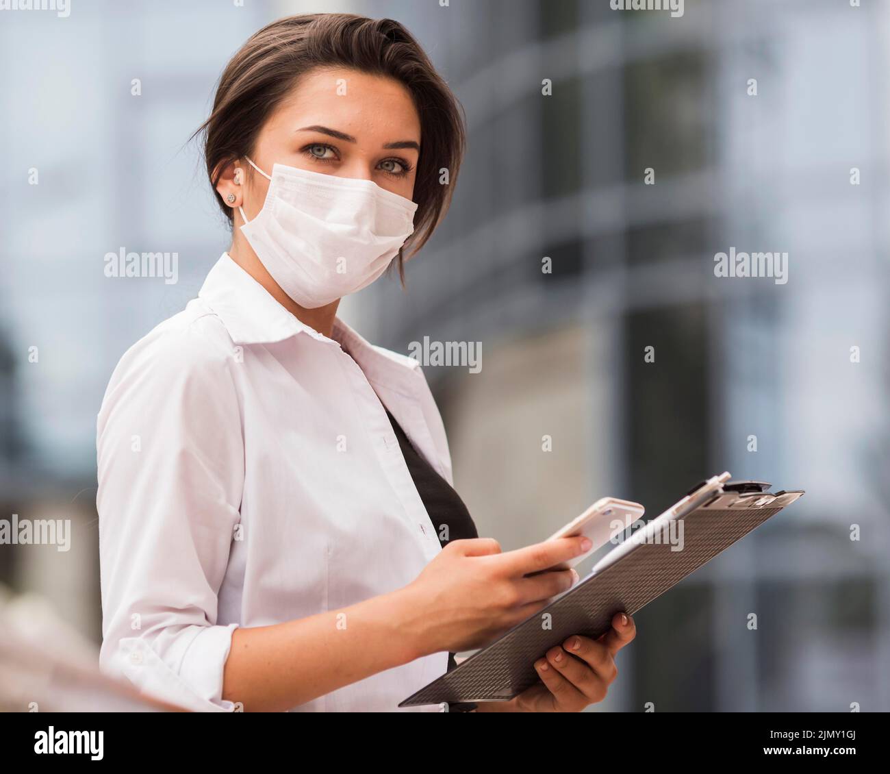 Side view woman working during pandemic with smartphone notepad Stock Photo