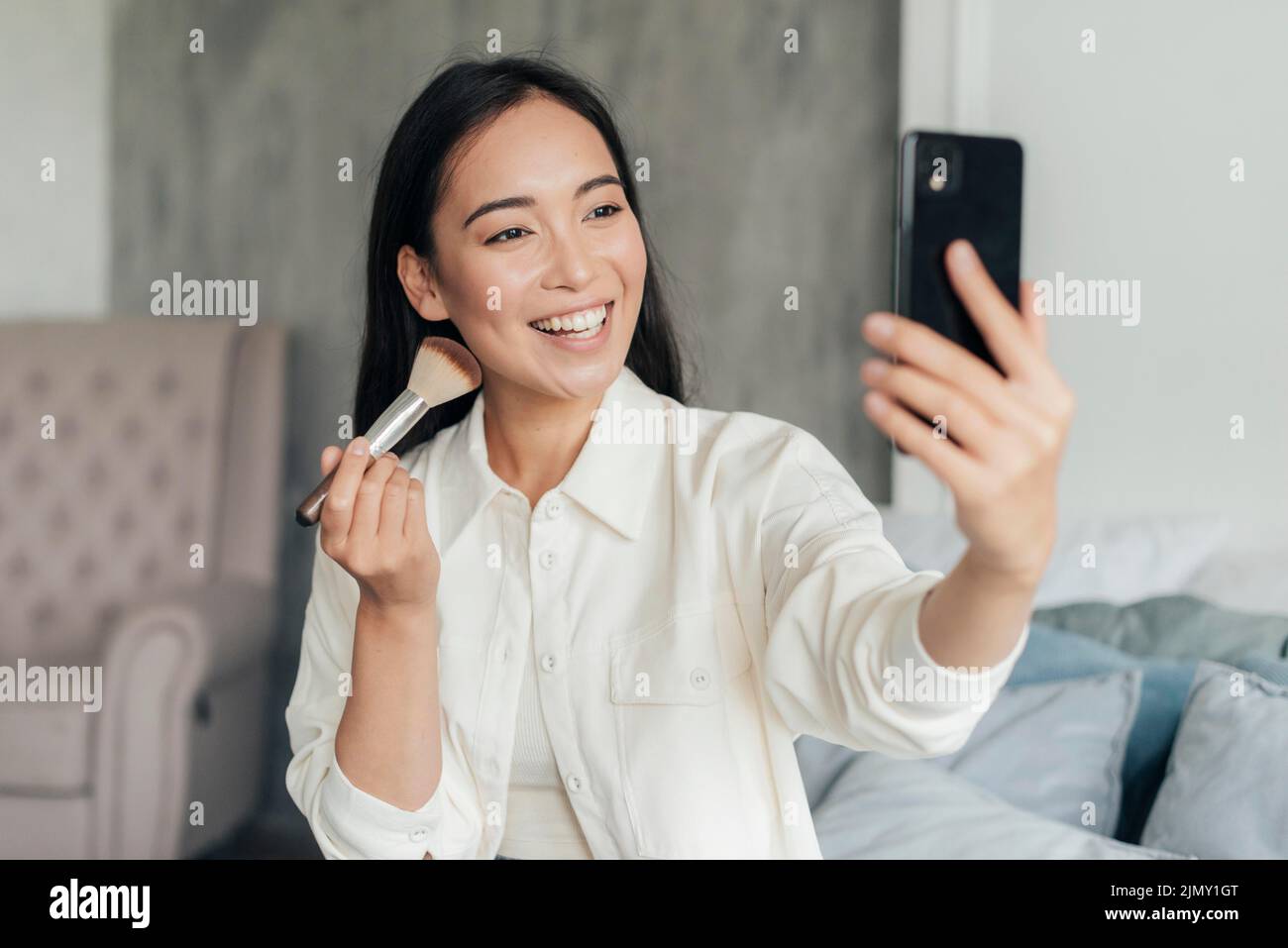 Smiley woman vlogging with make up brush Stock Photo