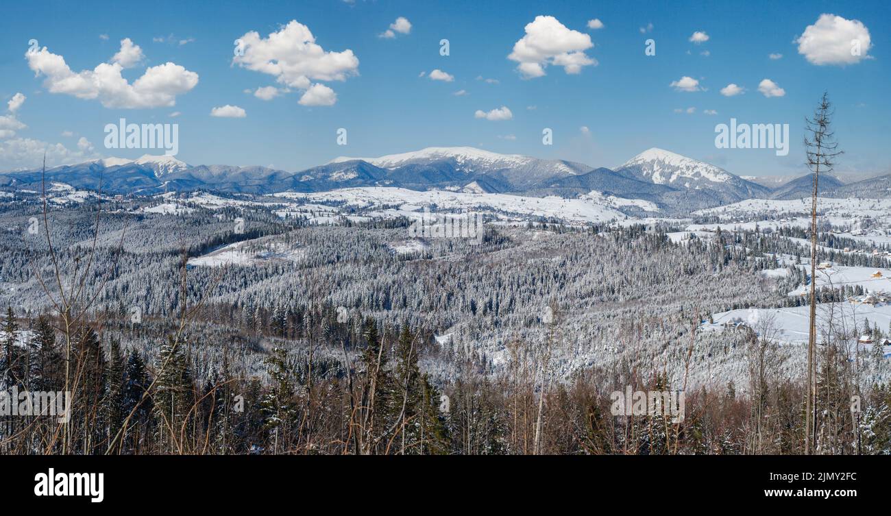 Winter remote alpine village outskirts, countryside hills, groves and farmlands view from mountain slope Stock Photo