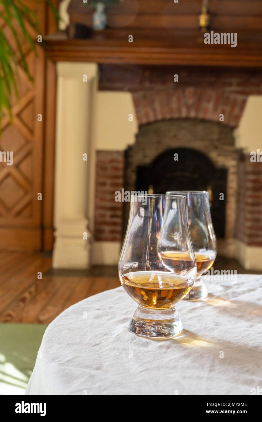 Two drams of scotch whiskey with view on fireplace in old house on