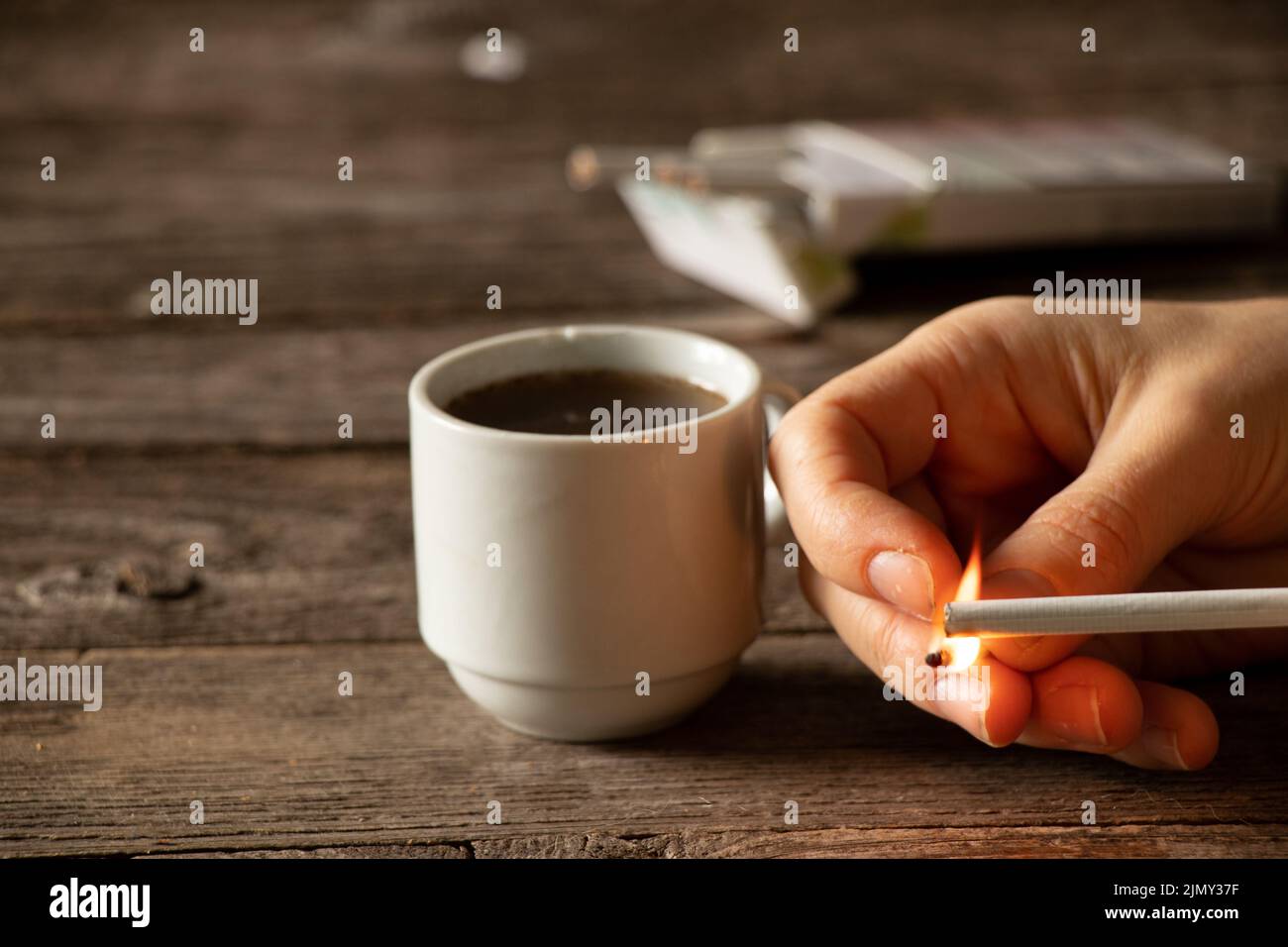 a cigarette in the hands of a girl on the table next to a cup of coffee, cigarettes and coffee, bad habits, smoking Stock Photo