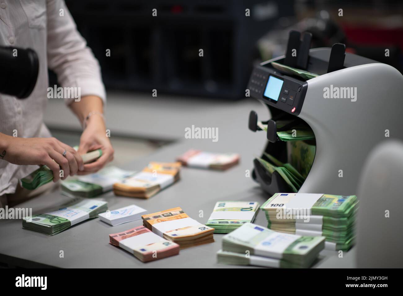 Bank employees using money counting machine while sorting and counting