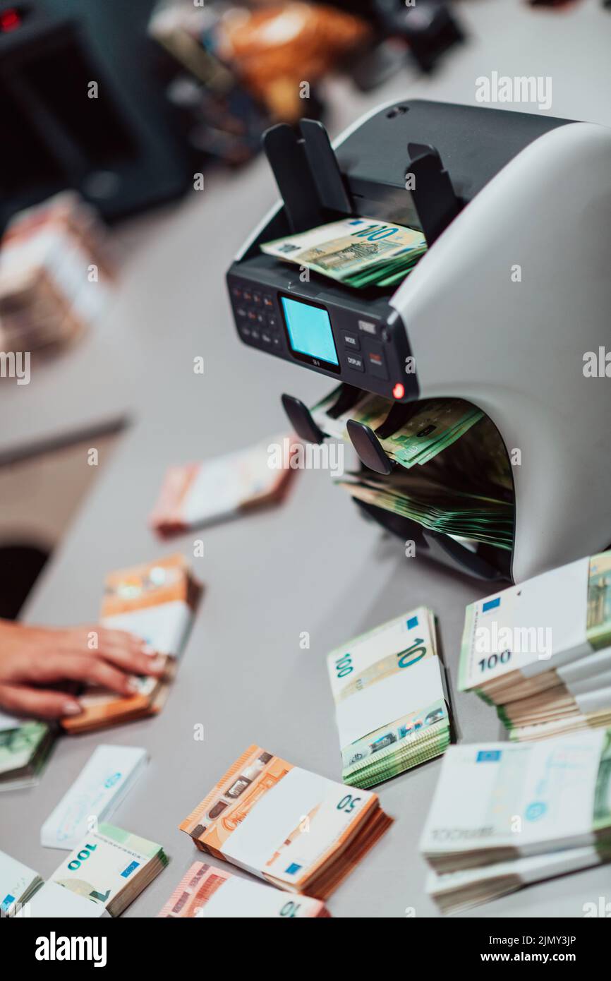 Bank employees using money counting machine while sorting and counting
