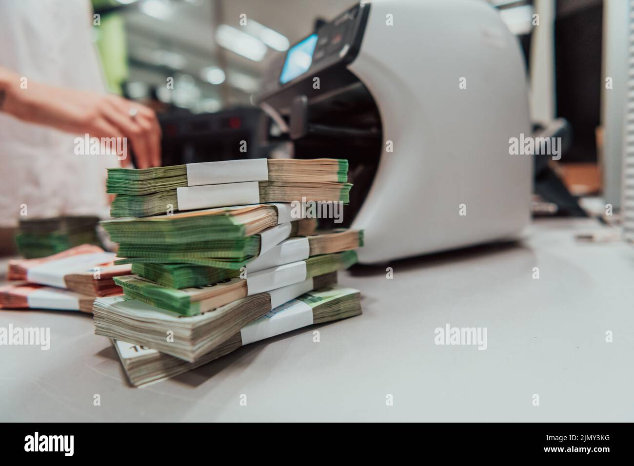 Bank employees using money counting machine while sorting and counting