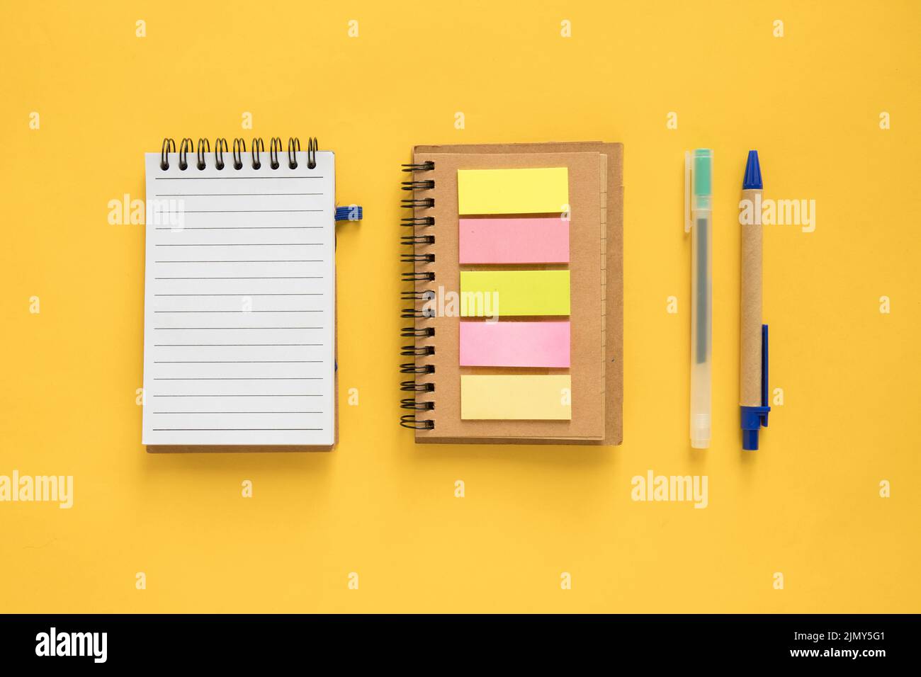 High angle view spiral notepad adhesive notes pen yellow background Stock Photo