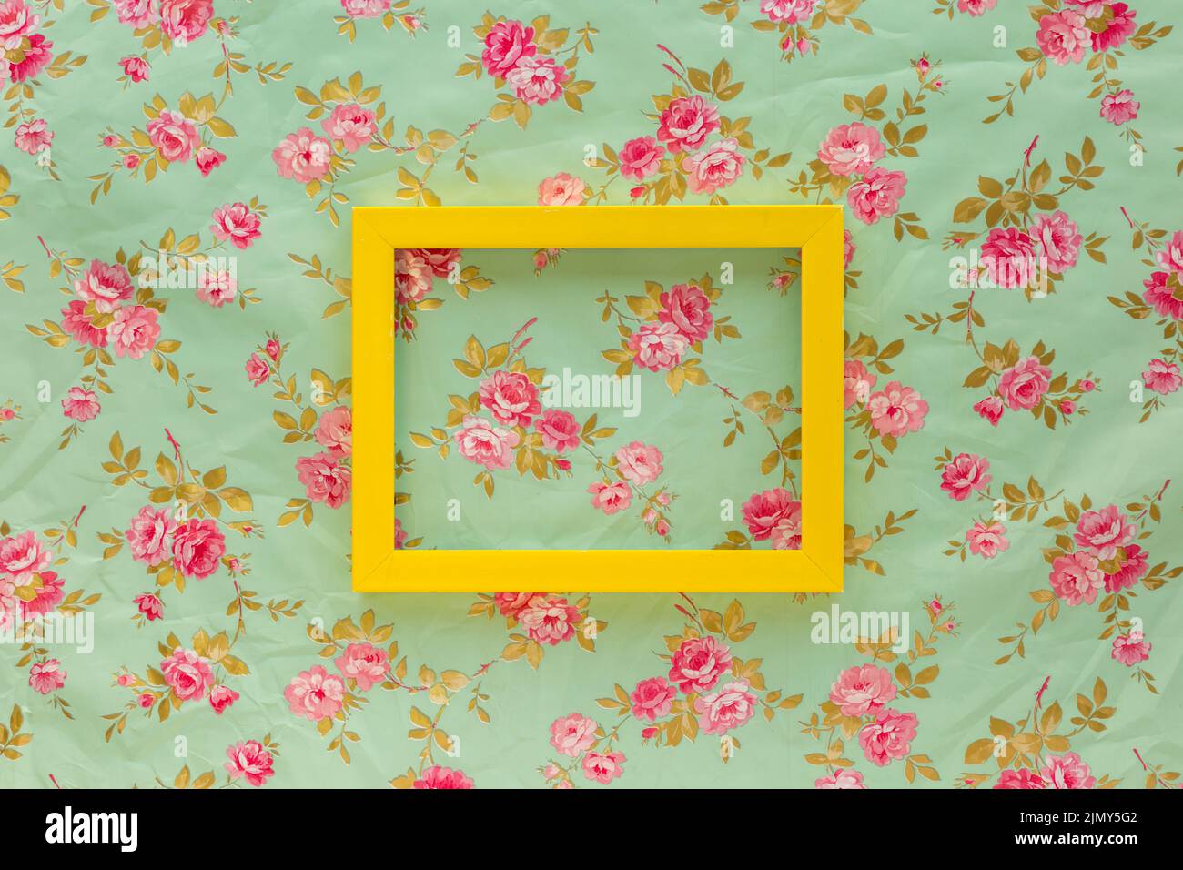 High angle view yellow empty frame against floral print background Stock Photo