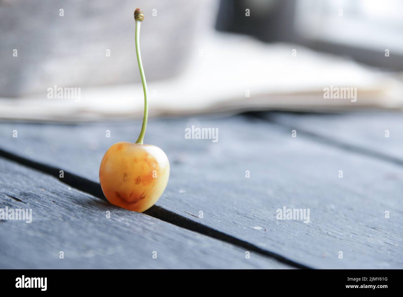 Advertising background. Yellow cherry with a painted smile. Stock Photo
