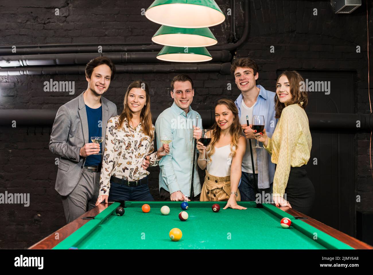 Group happy smiling friends with drinks standing snooker table Stock Photo