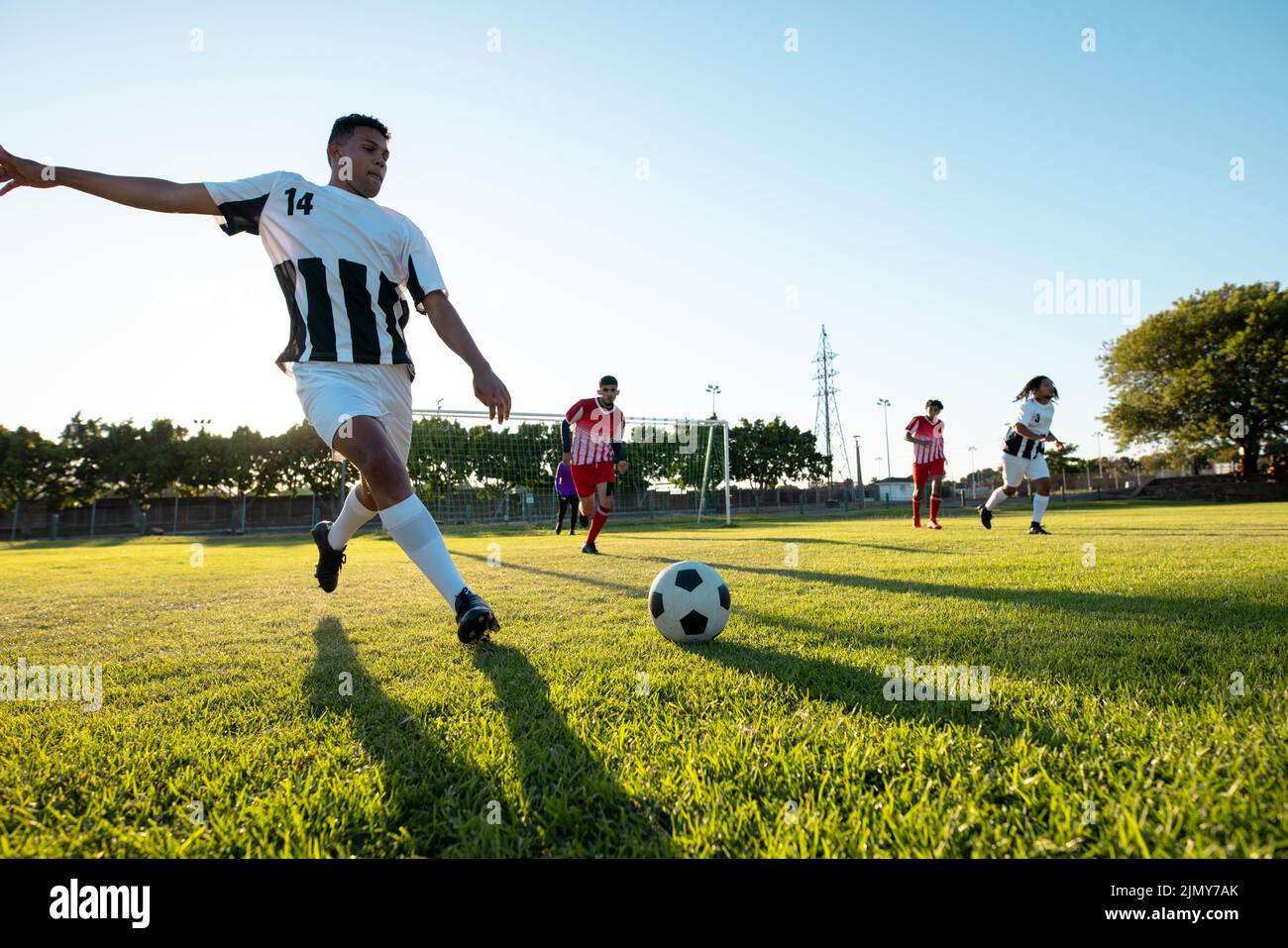 Multiracial player kicking ball while playing soccer match against
