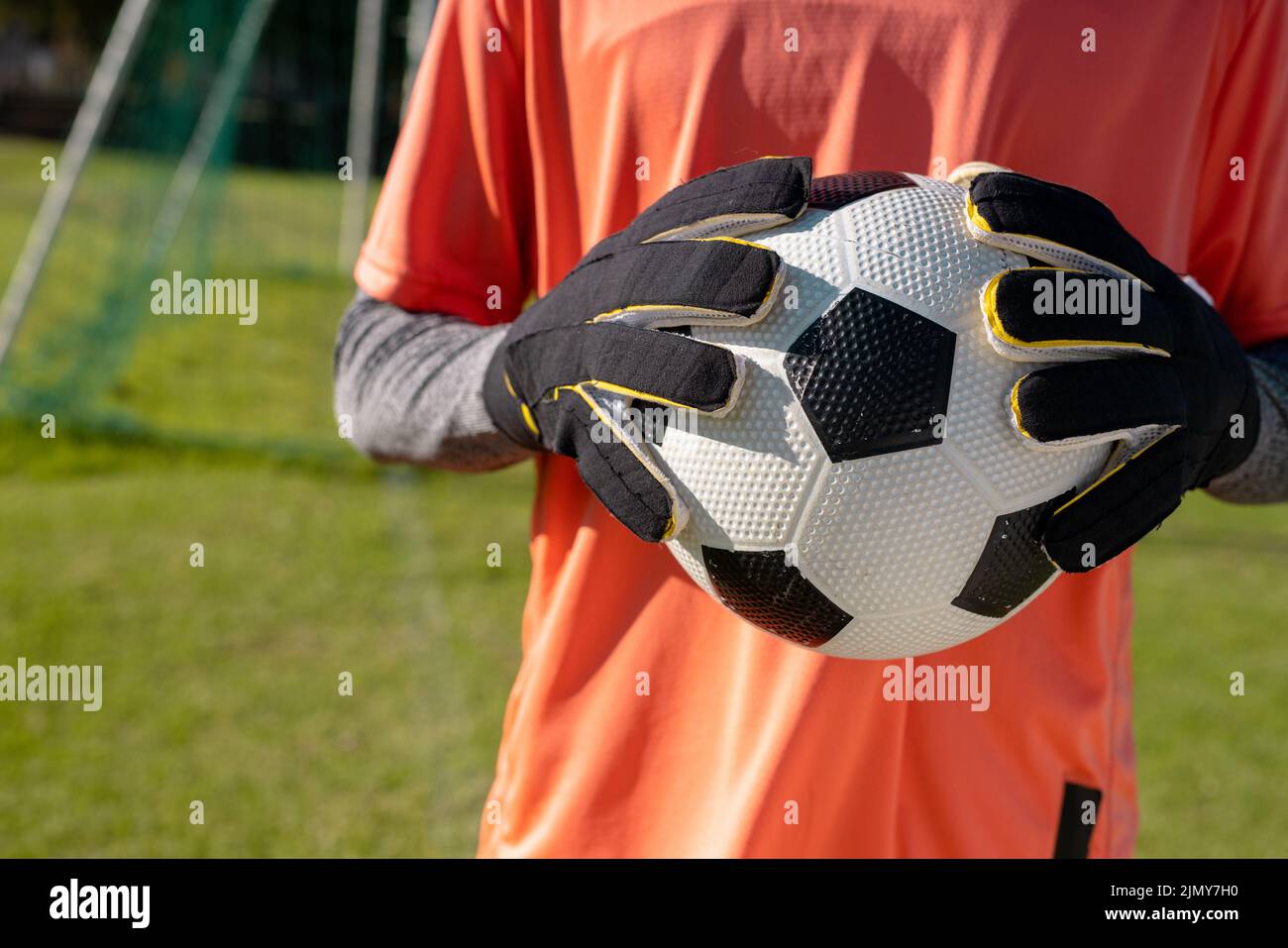 Midsection of african american male goalkeeper wearing gloves holding
