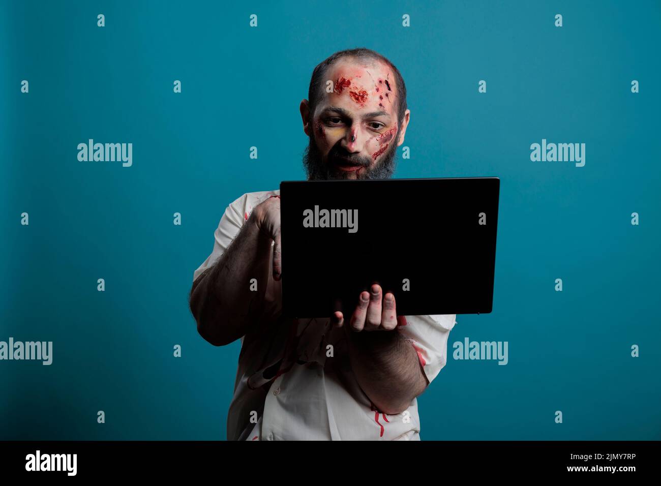 Dangerous halloween monster browsing on laptop in front of camera, holding computer and