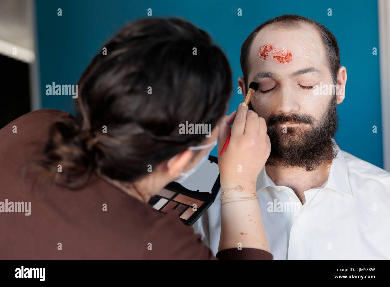 Artist using makeup effects to create zombie costume and scary dramatic