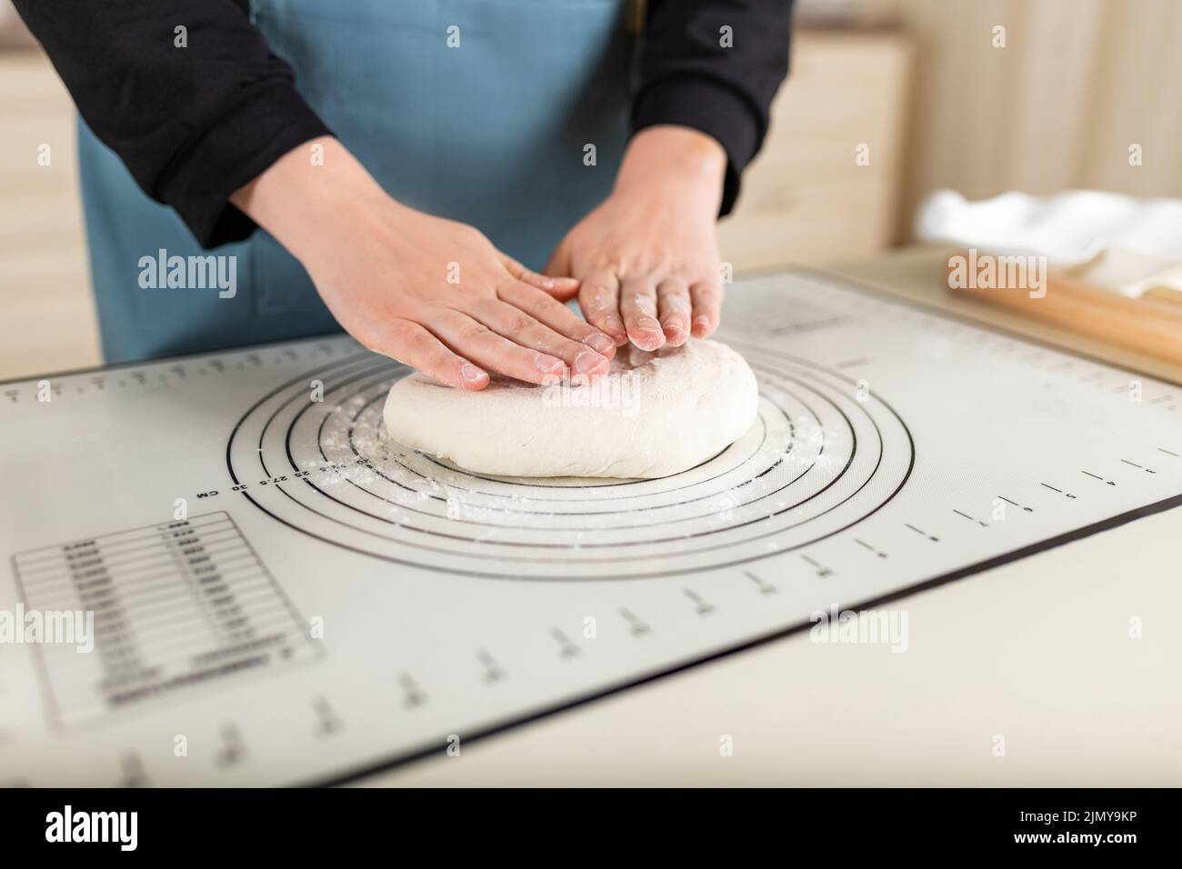 The cook's hands are ready to knead the wheat dough on a silicone