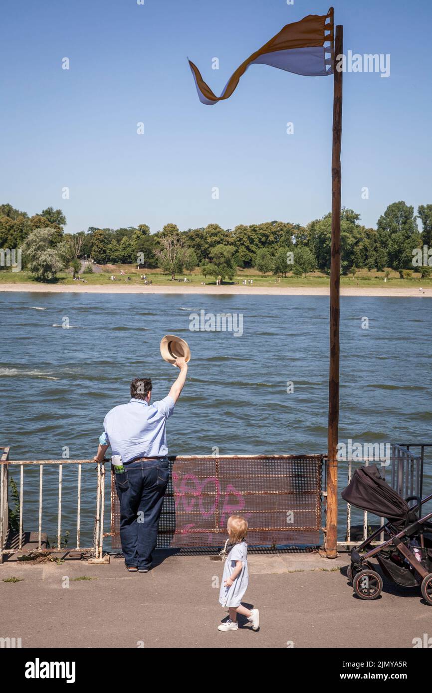 man standing on the banks of the Rhine in the Muelheim district, waving his hat, Cologne, Germany. Mann steht am Rheinufer im Stadtteil Muelheim und w Stock Photo