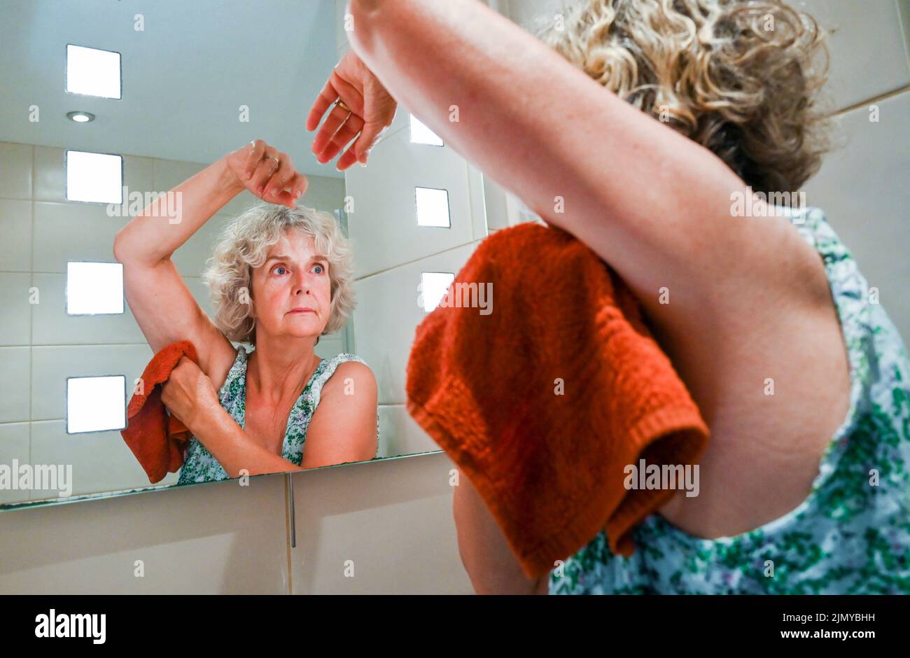 Woman washing with a flannel and soap at bathroom sink to save water as some areas of Britain are experiencing water shortages Stock Photo