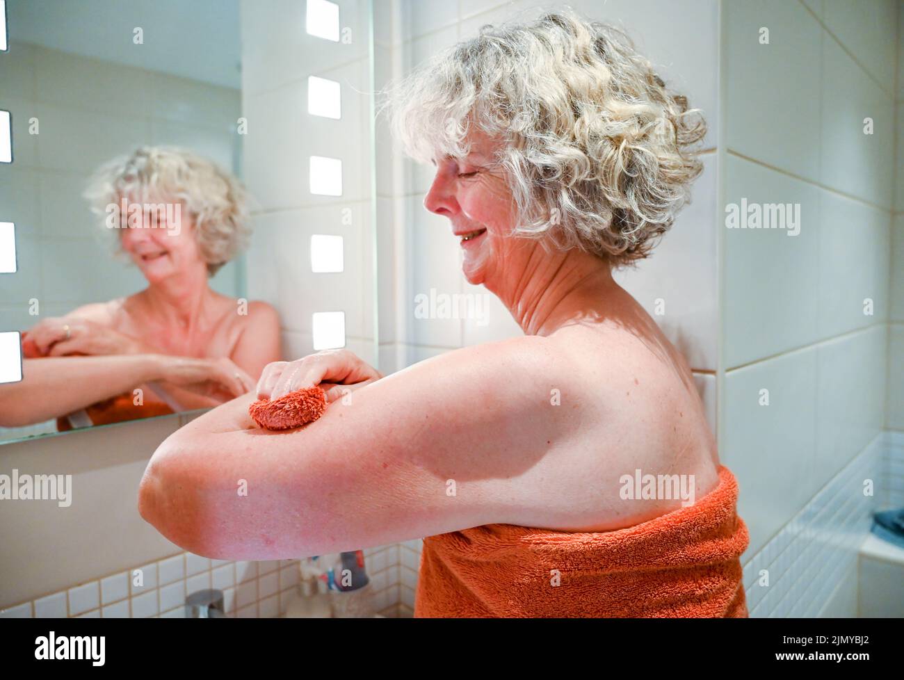 Woman washing with a flannel and soap at bathroom sink to save water as some areas of Britain are experiencing water shortages Stock Photo