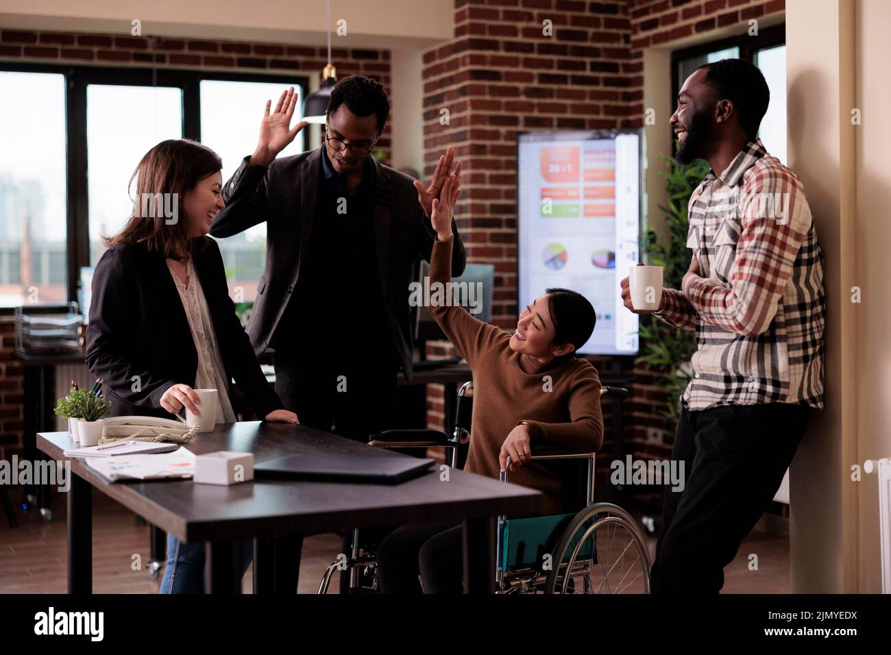 Female manager in wheelchair and group of people laughing on job break