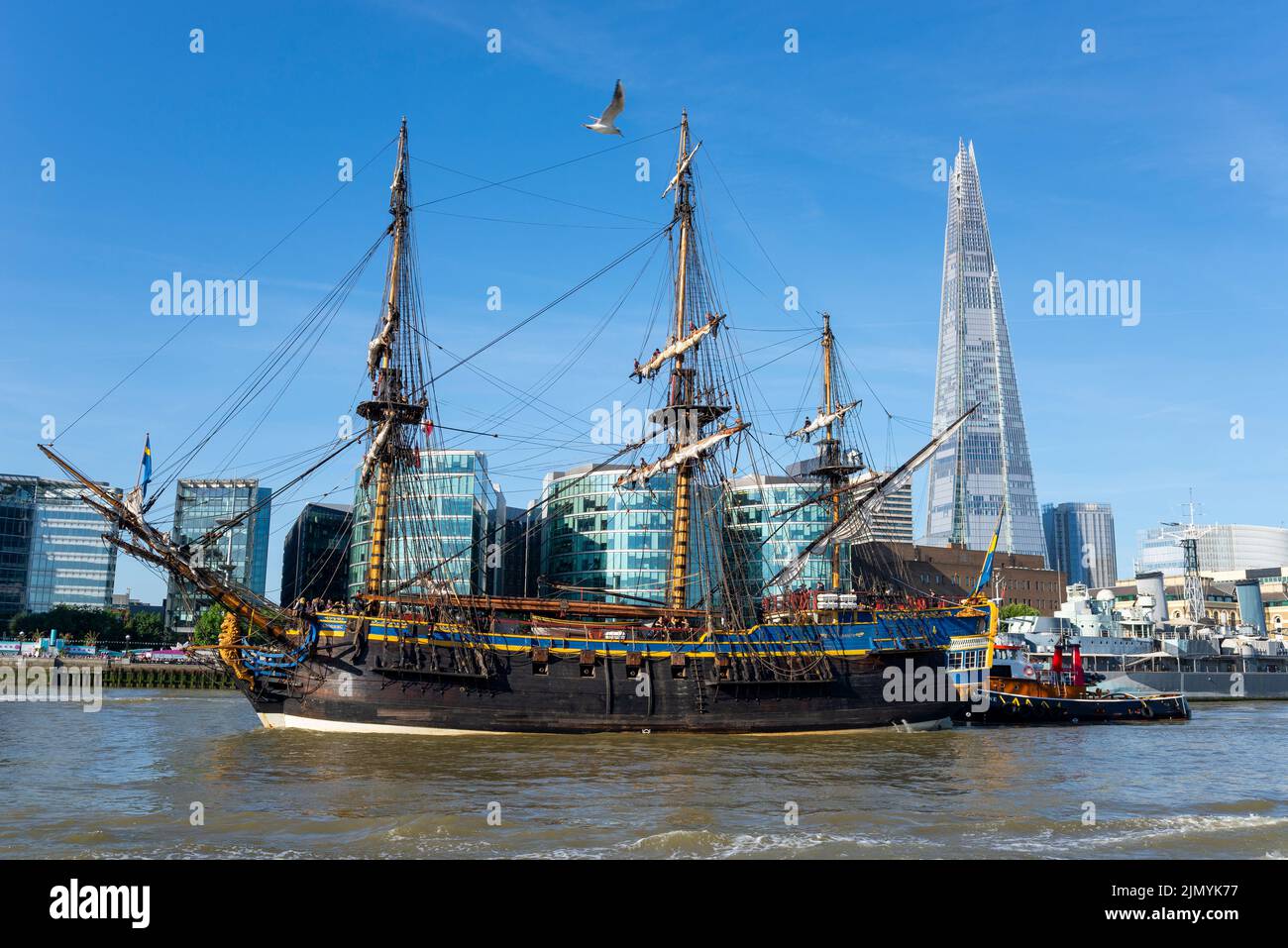 Tower Bridge, London, UK. 8th Aug, 2022. Gotheborg of Sweden is a sailing replica of the Swedish East Indiaman Gotheborg I, launched in 1738, and is visiting London to welcome visitors on board. The wooden replica ship was launched in 2003 and last visited London in 2007. It has navigated up the River Thames in the morning to pass under the opened Tower Bridge before turning and passing back under and heading for Thames Quay in Canary Wharf, where it will be open to visitors. Pushed by tug, passing HMS Belfast, The Shard and More London Stock Photo