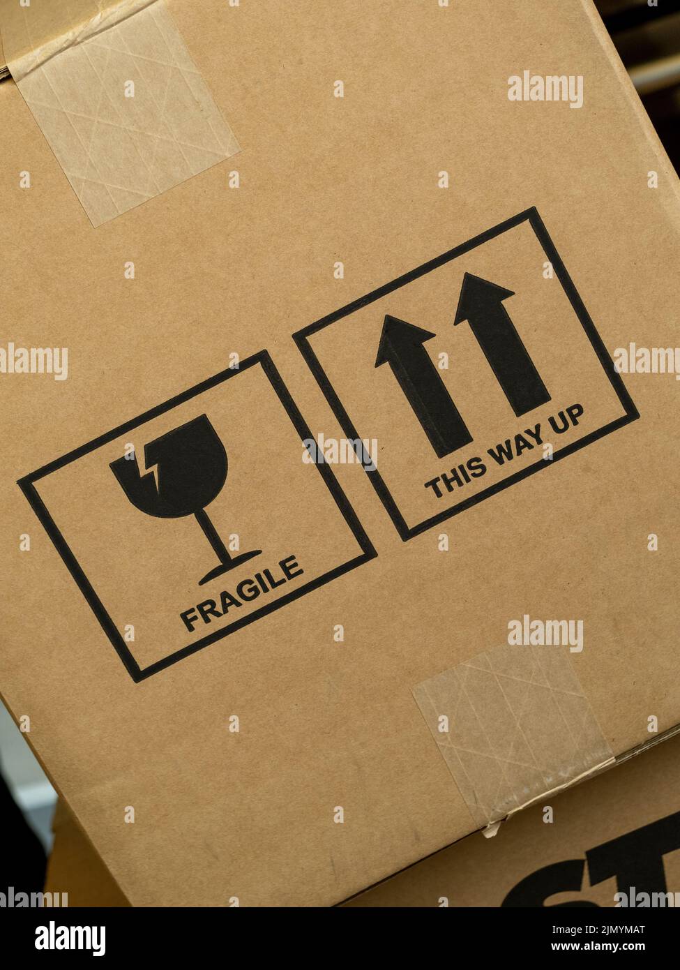 Angled cardboard box with the words Fragile and This Way Up, along with graphic icon symbols. Stock Photo
