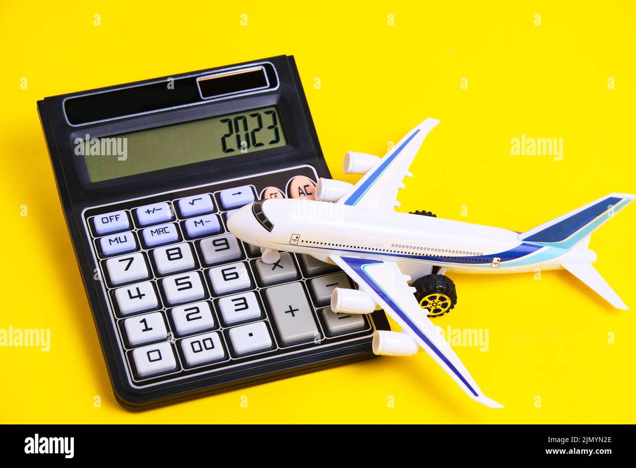 Airplane model and calculator yellow background.Concept of costs or