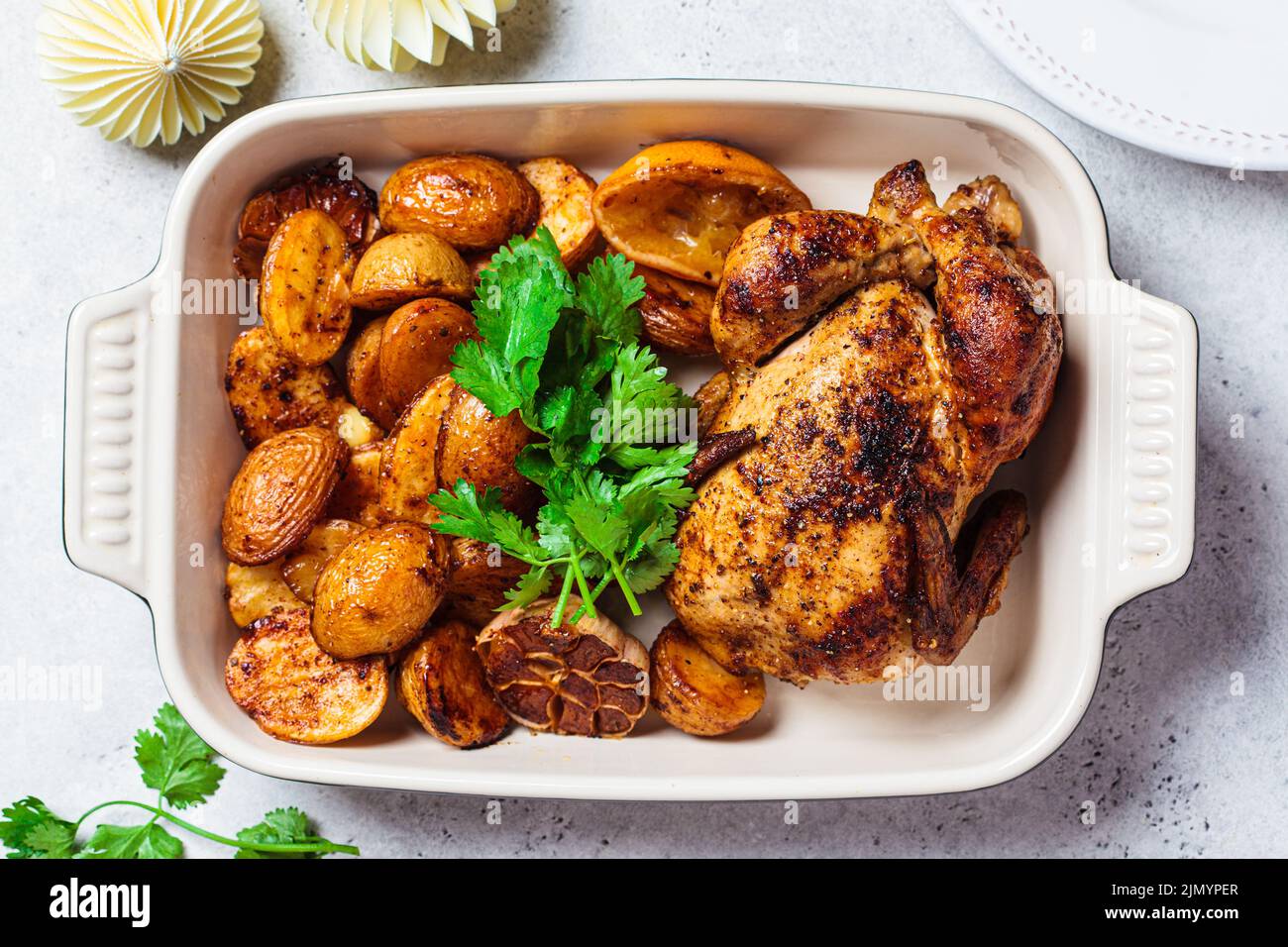 Baked whole chicken with potatoes in black oven tray for Christmas