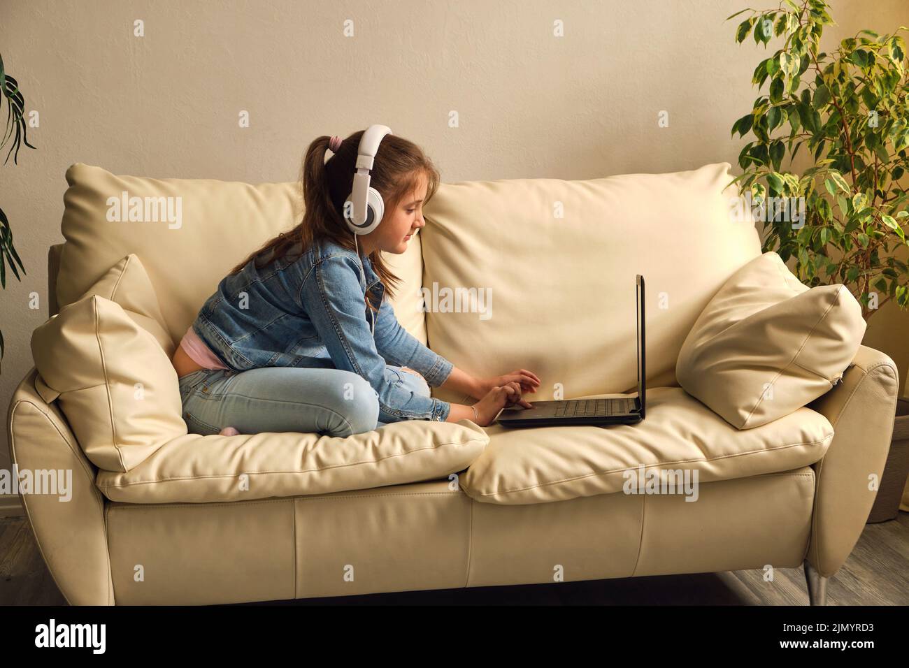 Kid girl with headphones looking video lesson Stock Photo Alamy