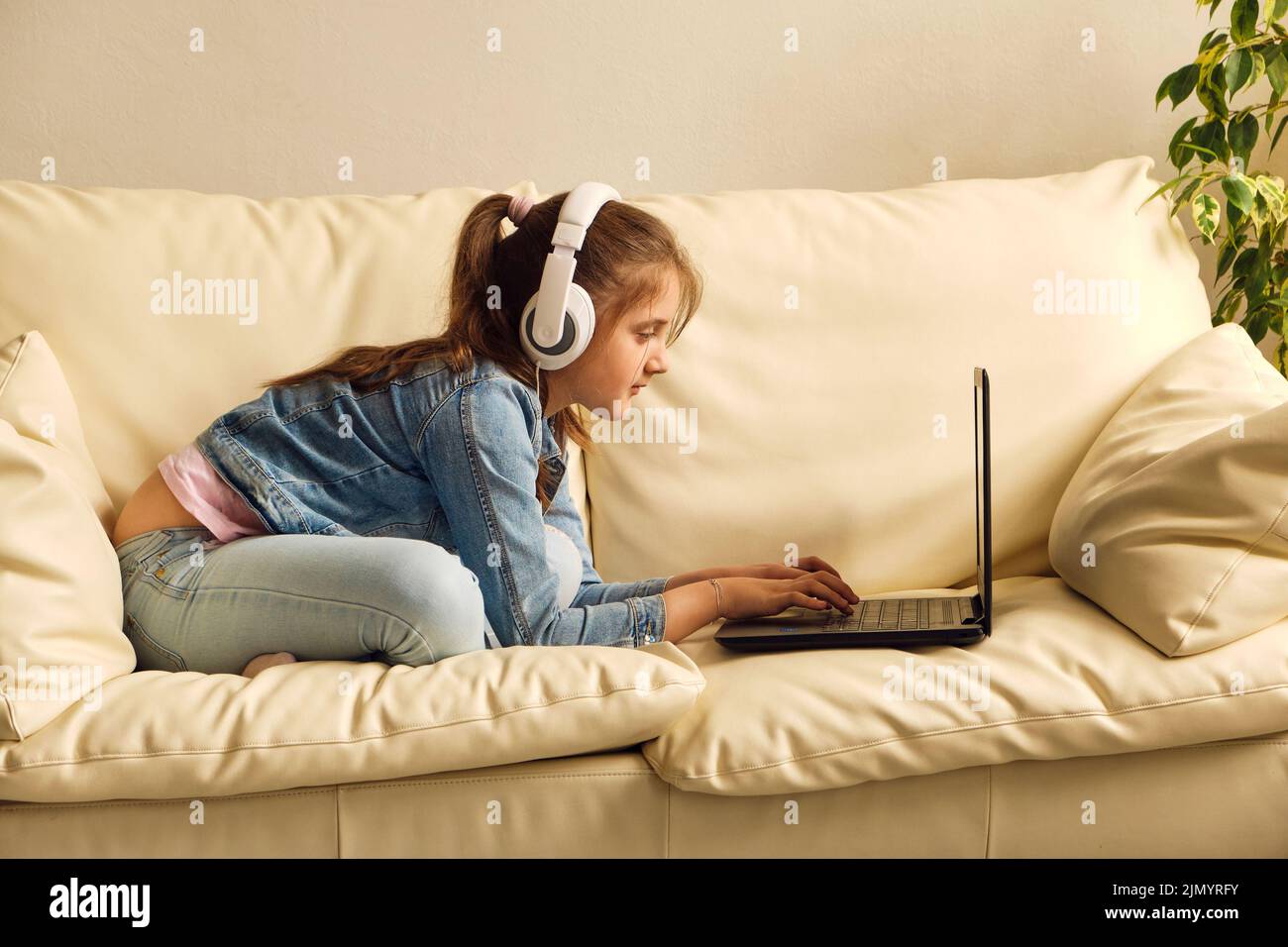Kid girl with headphones looking video lesson Stock Photo Alamy