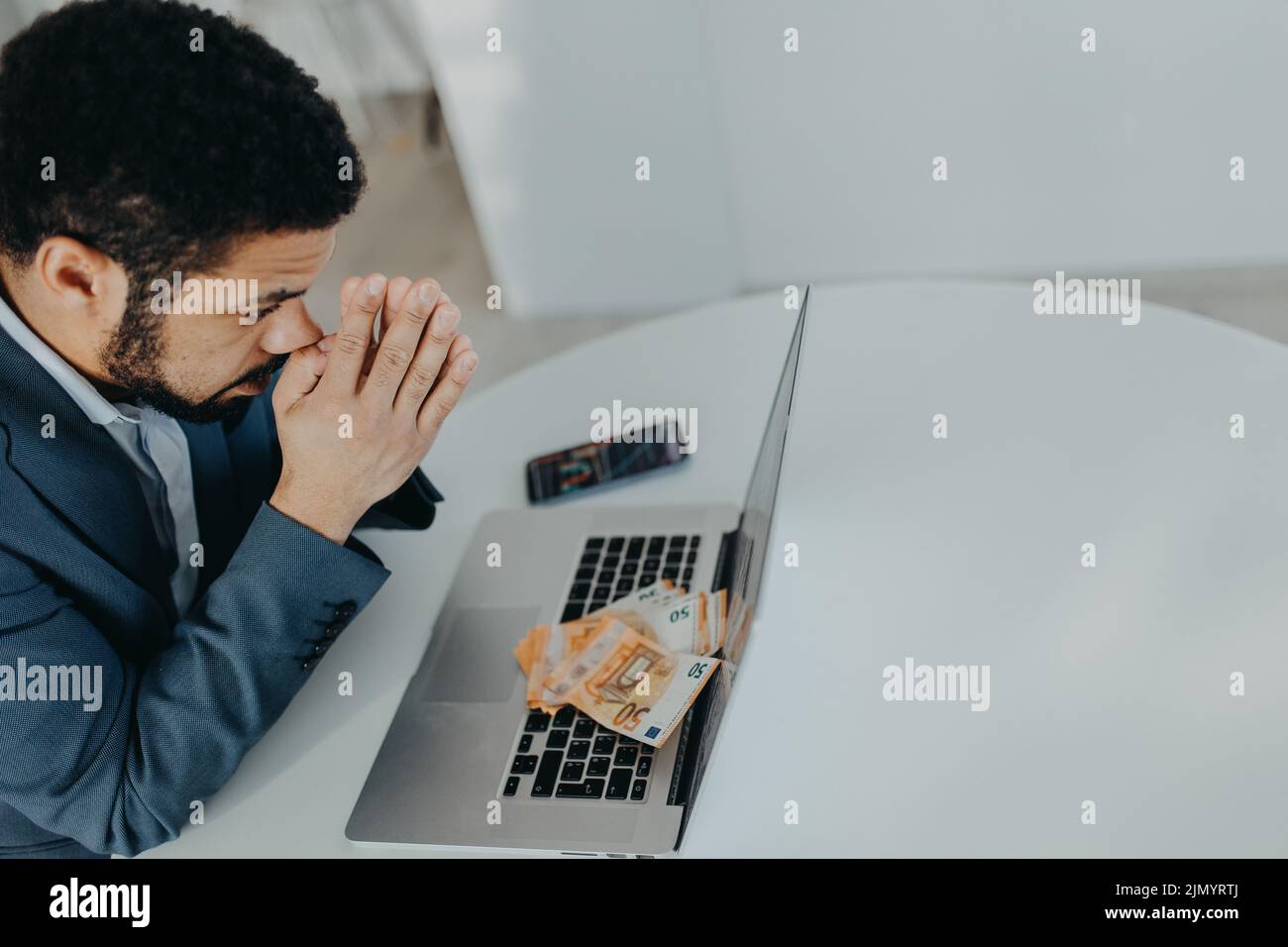 Depressed businessman man counting euro money working on computer at office desk, inflation concept. Stock Photo