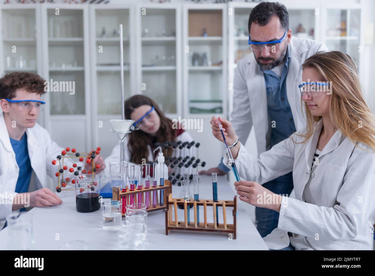 Science students with teacher doing chemical reaction experiment in the laboratory at university. Stock Photo
