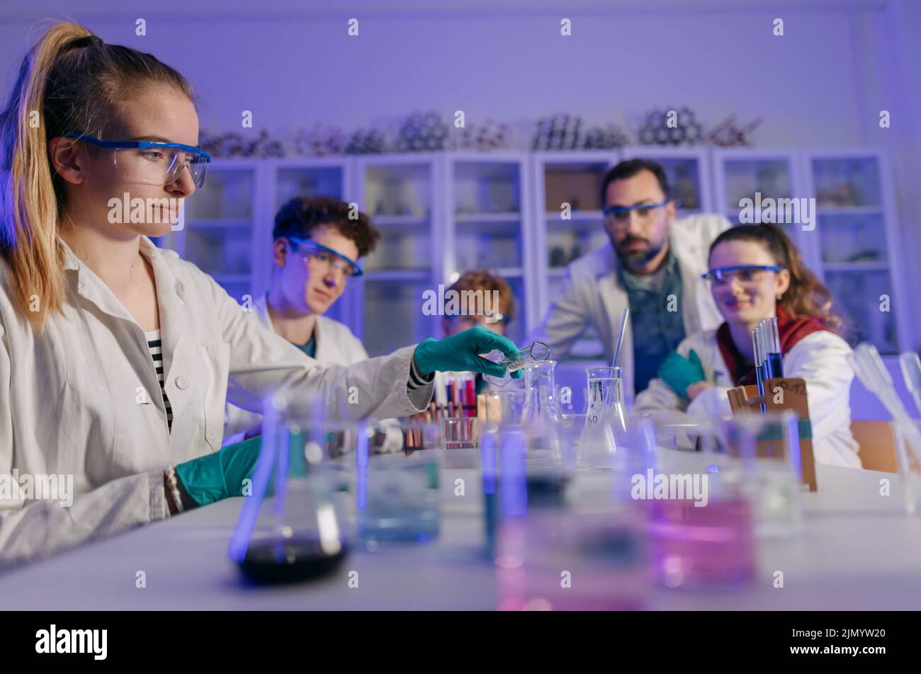 Excited science students with teacher doing chemical experiment in the laboratory at university. Stock Photo