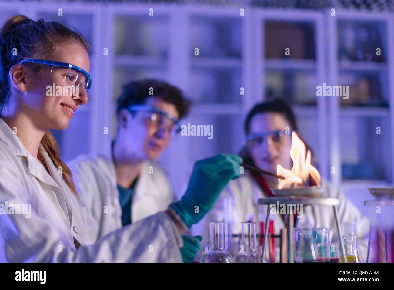 Excited science students with teacher doing chemical experiment in the laboratory at university. Close-up. Stock Photo