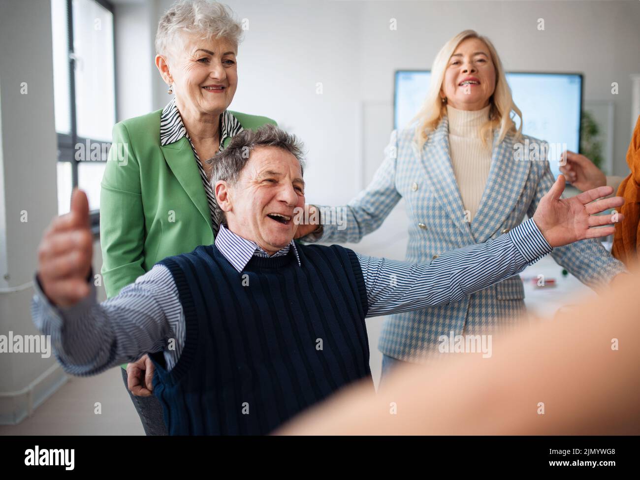 Happy senior students meeting and hugging in classroom. Stock Photo